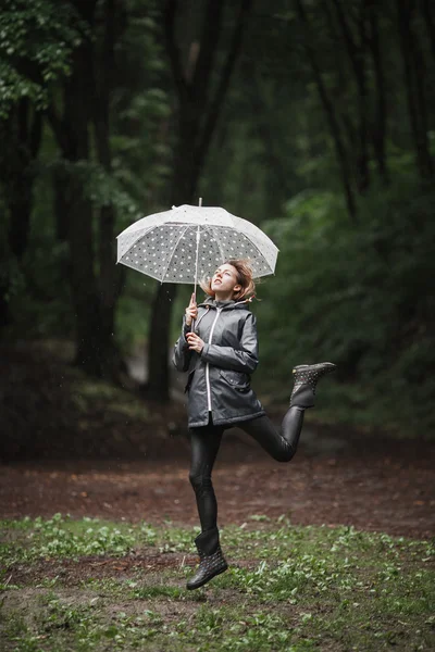 Junges Mädchen läuft mit Regenschirm durch einen Regenwald. — Stockfoto