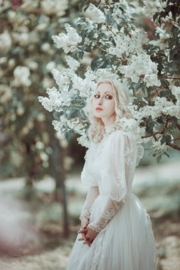 Beautiful blonde woman in blooming lilac garden. Vintage bride c clipart