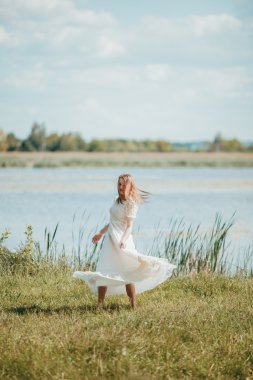 Vintage gelinlik güneşin Nehri yakınında yürüyüş güzel genç bayan.