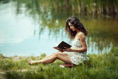 Yeşil çimenlerin üzerinde eğitim güzel genç kız. Kitap okuma