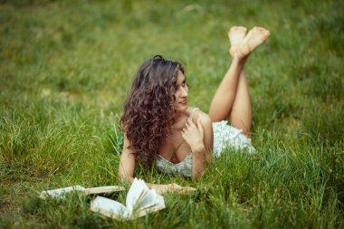 Yeşil çimenlerin üzerinde eğitim güzel genç kız. Kitap okuma