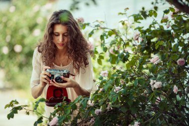 Güzel kız çekim bir gül ile eski fotoğraf makinesi.