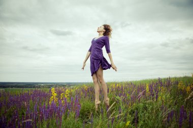 Adaçayı çiçek alanda yürüyüş vintage elbiseli genç kız.