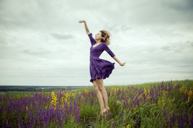 Adaçayı çiçek alanda yürüyüş vintage elbiseli genç kız.