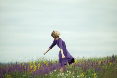 Adaçayı çiçek alanda yürüyüş vintage elbiseli genç kız.