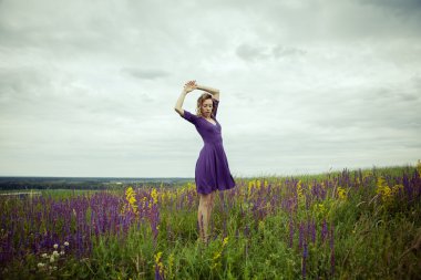 Adaçayı çiçek alanda yürüyüş vintage elbiseli genç kız.