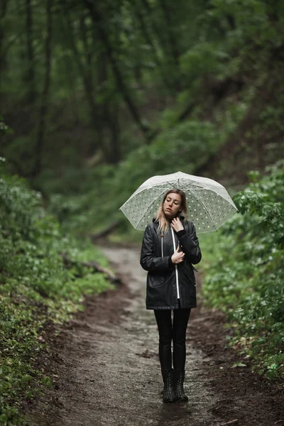 Chica joven caminando a través de un bosque lluvioso con paraguas . —  Fotos de Stock