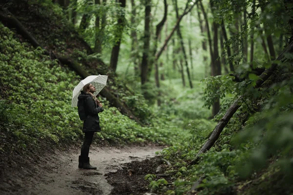 Young girl walking through a rainy forest with umbrella. — Stock Photo, Image