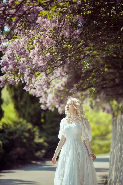 Zahrada krásná blondýnka v kvetoucí šeřík. Vintage nevěsta koncept — Stock fotografie