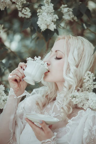 Beautiful blonde woman in blooming lilac garden. Vintage. Alice. — Stock Photo, Image