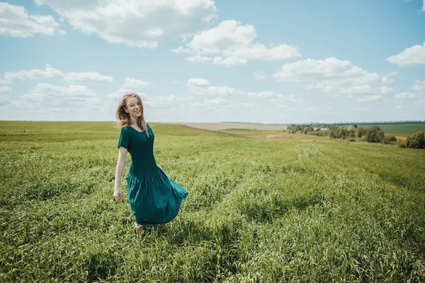 Hermosa joven en vestido verde caminando en el campo de verano . —  Fotos de Stock