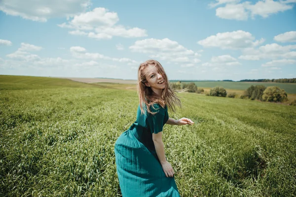Bella ragazza in abito verde a piedi nel campo estivo . — Foto Stock