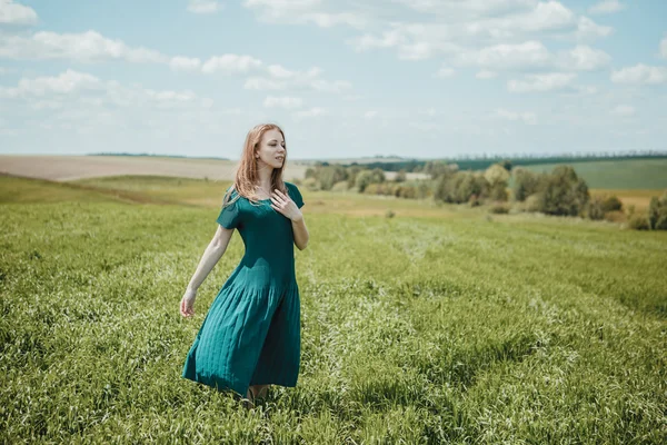 Hermosa joven en vestido verde caminando en el campo de verano . —  Fotos de Stock