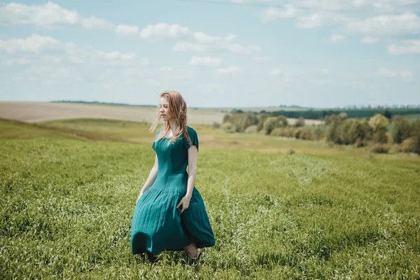 Bella ragazza in abito verde a piedi nel campo estivo . — Foto Stock