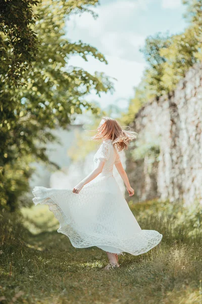 Belle jeune fille en robe vintage blanche marchant près de l'ancien château . — Photo