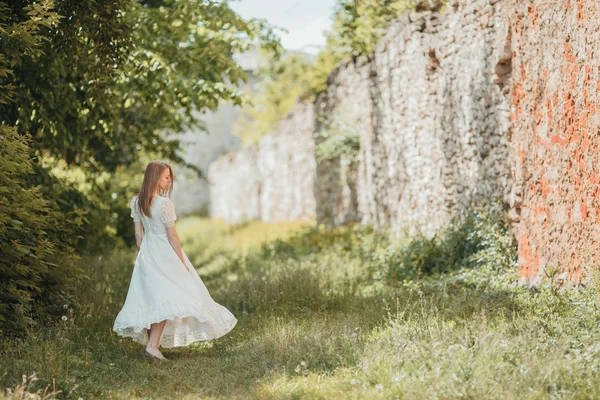 Hermosa joven en vestido vintage blanco caminando cerca del antiguo castillo . — Foto de Stock