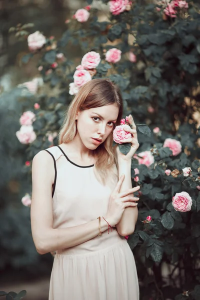 Красивая молодая девушка в модном розовом платье, нюхающая розы. Сказка. Мода. Фантазия — стоковое фото