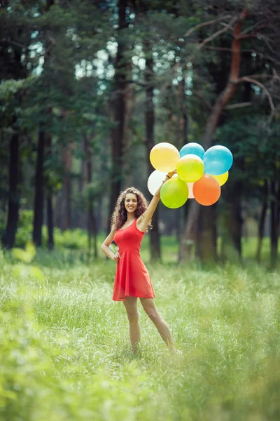 Belle jeune fille qui s'amuse au parc d'été avec des ballons colorés. Joyeux sourire concept de saut — Photo