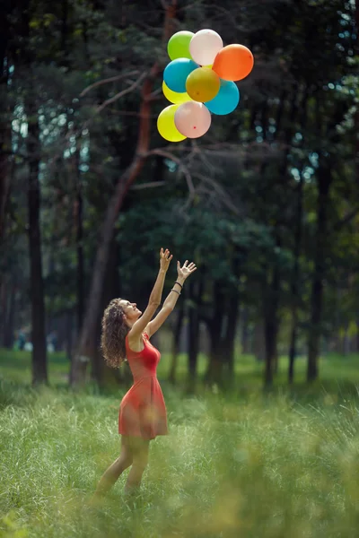 Mooi jong meisje, plezier in het park van de zomer met gekleurde ballonnen. Happy glimlach sprong concept — Stockfoto