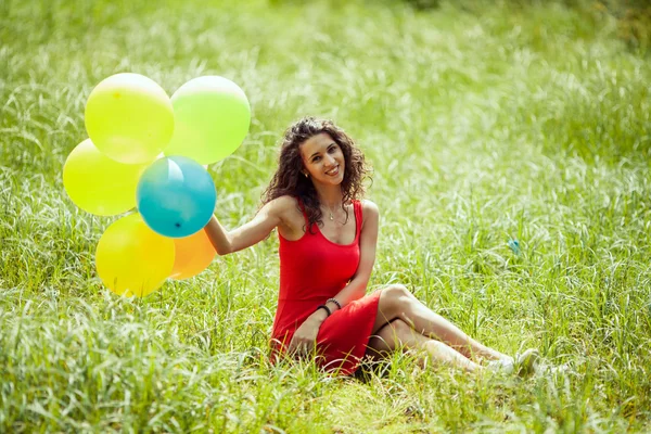 Красива молода дівчина розважається в літньому парку з кольоровими повітряними кулями. Щаслива концепція стрибка посмішки — стокове фото