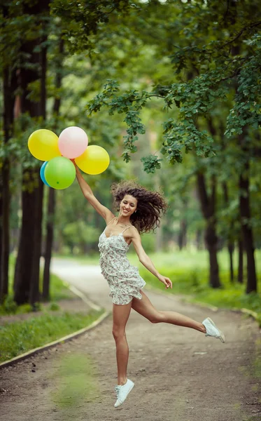 Schöne junge Mädchen Spaß im Sommerpark mit bunten Luftballons. glückliches Lächeln Sprungkonzept — Stockfoto