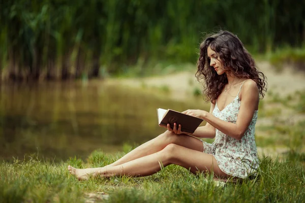 Красивая молодая девушка учится на зеленой траве. Чтение книг — стоковое фото