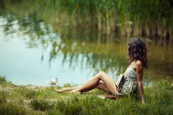 Mooi jong meisje studeren op groen gras. Lezen van boeken — Stockfoto