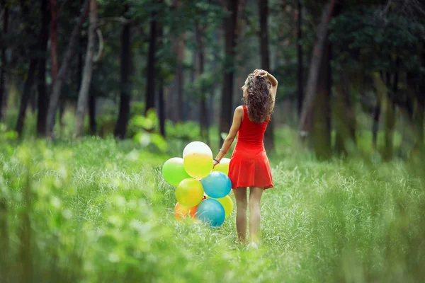 Belle jeune fille qui s'amuse au parc d'été avec des ballons colorés. Joyeux sourire concept de saut — Photo