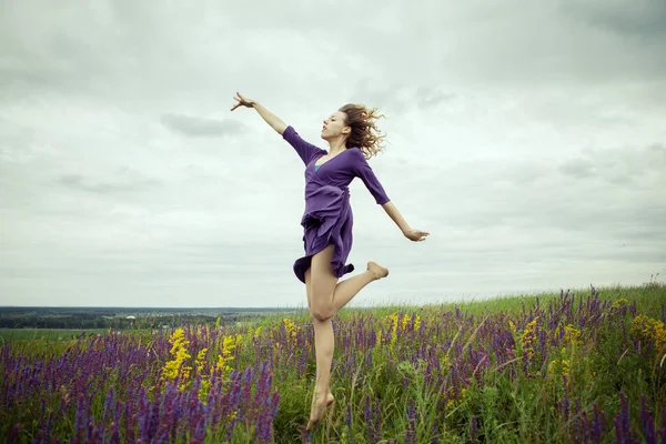 Jeune fille en robe vintage marchant à travers le champ de fleurs de sauge . — Photo