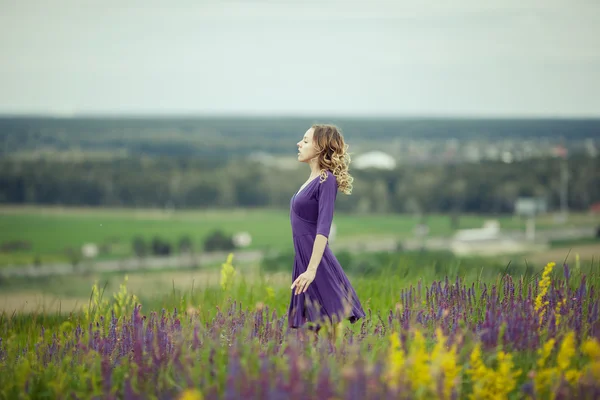 Young girl in vintage dress walking through sage flower field. — Stock Photo, Image