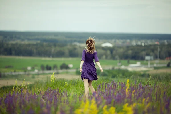 Young girl in vintage dress walking through sage flower field. — Stock Photo, Image