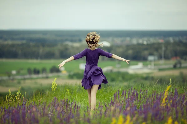 Menina jovem em vestido vintage andando através do campo de flores sábio . — Fotografia de Stock