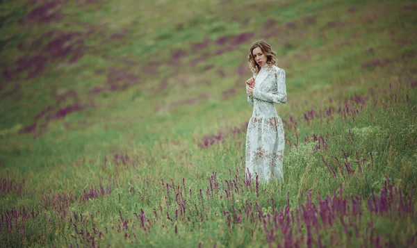 Молодая девушка в винтажном платье ходит по полю шалфея цветок . — стоковое фото