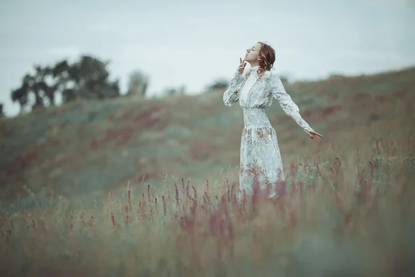 Jeune fille en robe vintage marchant à travers le champ de fleurs de sauge . — Photo