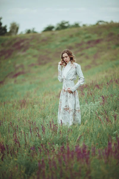 Chica joven en vestido vintage caminando por el campo de flores de salvia . —  Fotos de Stock