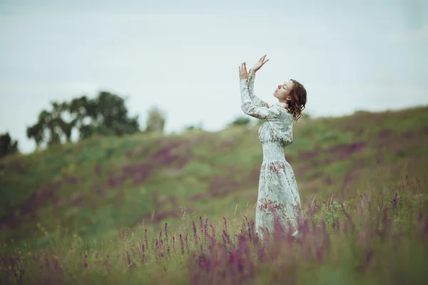 Chica joven en vestido vintage caminando por el campo de flores de salvia . — Foto de Stock