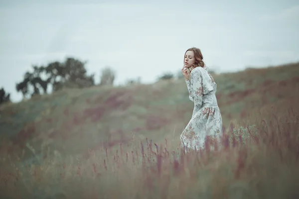 Chica joven en vestido vintage caminando por el campo de flores de salvia . —  Fotos de Stock