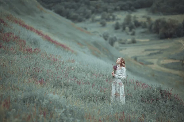 Chica joven en vestido vintage caminando por el campo de flores de salvia . — Foto de Stock