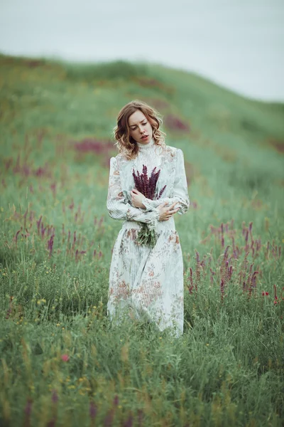 Chica joven en vestido vintage caminando por el campo de flores de salvia . —  Fotos de Stock