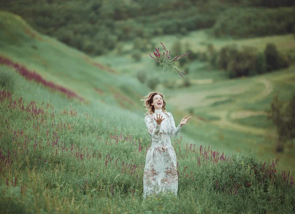 Giovane ragazza in abito vintage a piedi attraverso il campo di fiori salvia . — Foto Stock