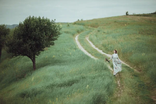 Chica joven en vestido vintage caminando por el campo de flores de salvia . — Foto de Stock