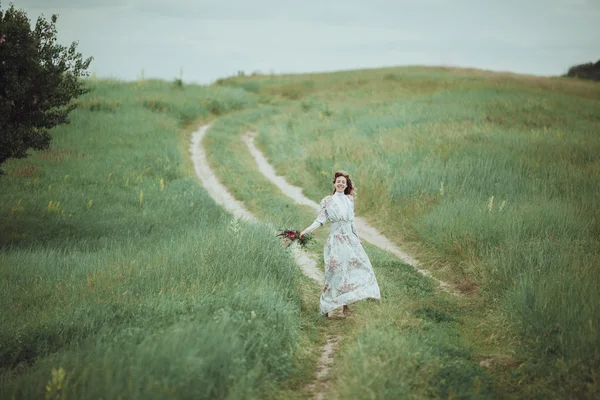 Chica joven en vestido vintage caminando por el campo de flores de salvia . — Foto de Stock