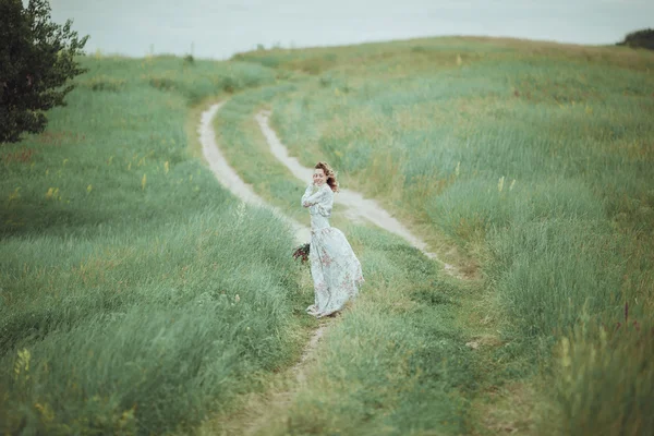 Chica joven en vestido vintage caminando por el campo de flores de salvia . — Foto de Stock