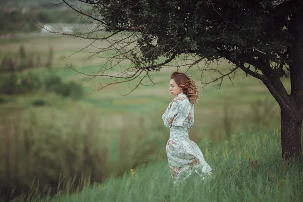 Mladá dívka v vintage šaty stojící poblíž osamělý strom — Stock fotografie