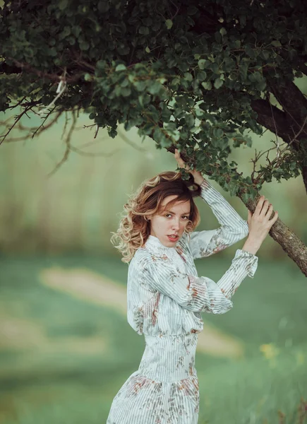 Menina jovem em vestido vintage em pé perto de árvore solitária — Fotografia de Stock
