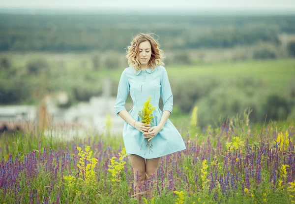 Chica joven en vestido vintage caminando por el campo de flores de salvia . —  Fotos de Stock