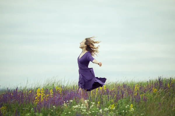 Junges Mädchen im Vintage-Kleid geht durch Salbeiblumenfeld. — Stockfoto