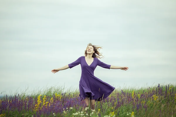 Junges Mädchen im Vintage-Kleid geht durch Salbeiblumenfeld. — Stockfoto
