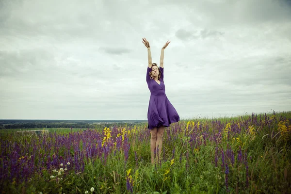 Giovane ragazza in abito vintage a piedi attraverso il campo di fiori salvia . — Foto Stock