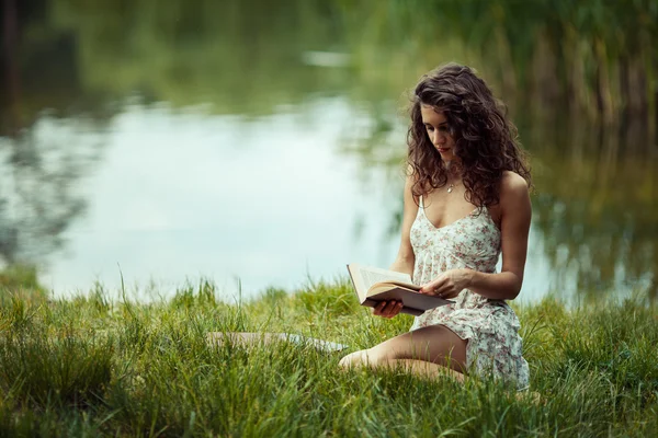 緑の草の上勉強していた美しい若い少女。本を読んで ストックフォト